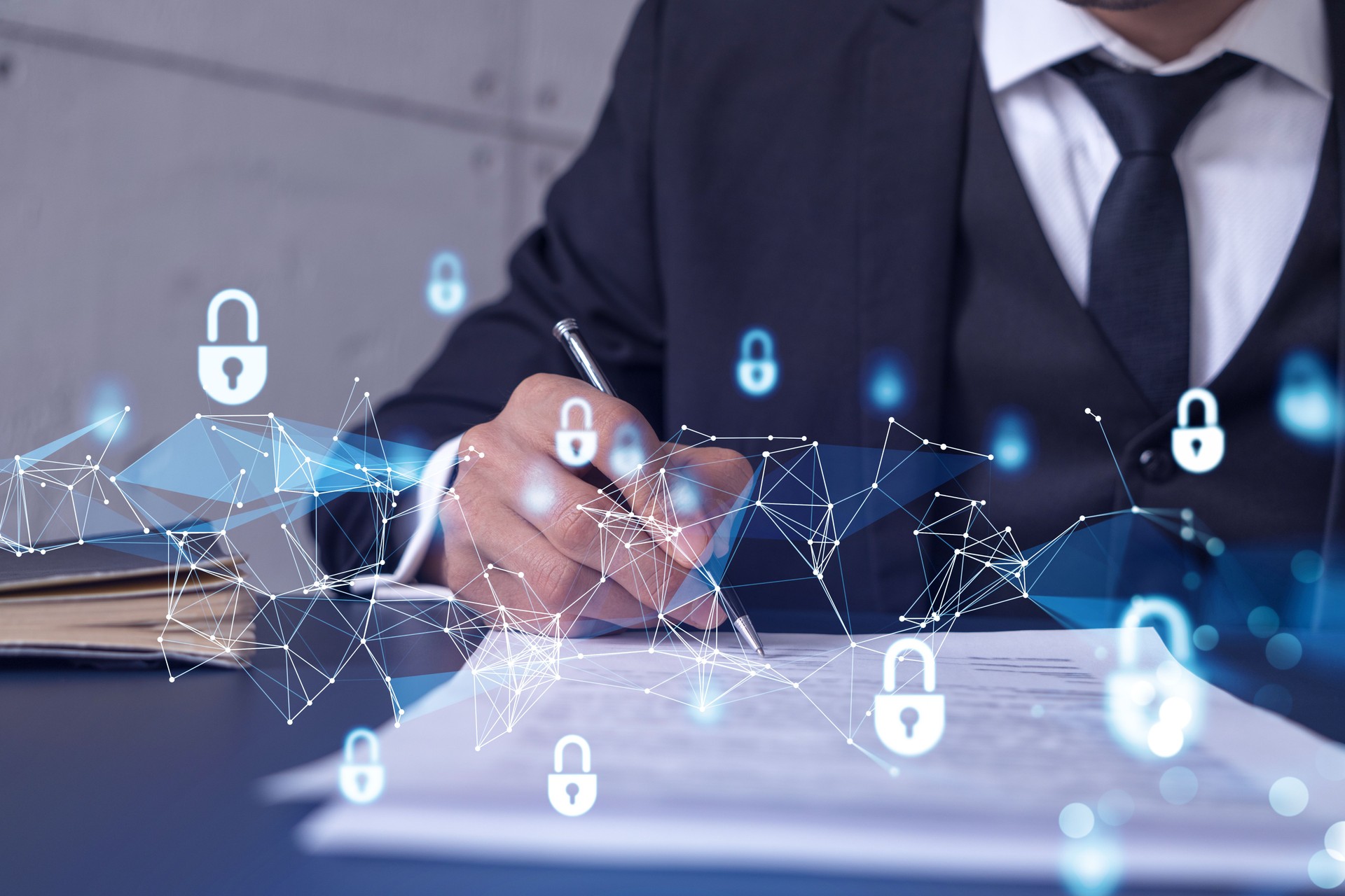 A businessman in formal wear signing the contract to prevent probability of risks in cyber security. Padlock Hologram icons over the working desk.